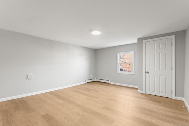 unfurnished room with a baseboard heating unit and light hardwood / wood-style floors