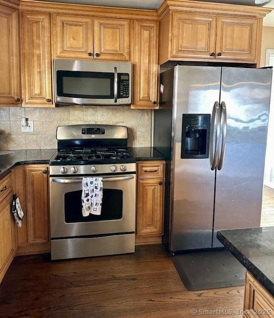 kitchen featuring stainless steel appliances, backsplash, dark hardwood / wood-style floors, and dark stone counters