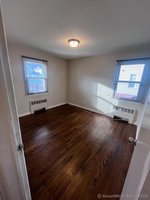 unfurnished room with dark hardwood / wood-style floors and radiator