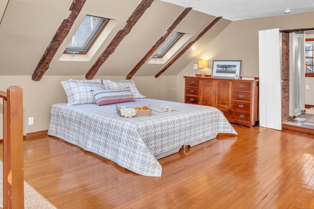 bedroom featuring lofted ceiling with skylight and light hardwood / wood-style flooring