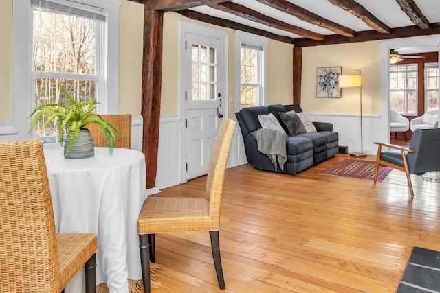 living room with beam ceiling, ceiling fan, a wealth of natural light, and hardwood / wood-style floors