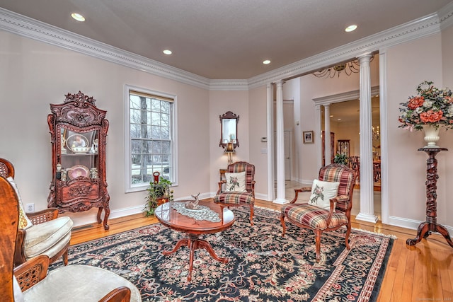 living area with light wood-type flooring, ornate columns, and crown molding