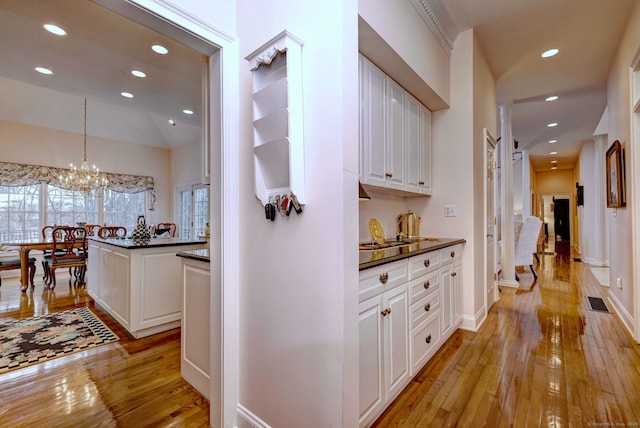 hall with vaulted ceiling, light hardwood / wood-style flooring, and an inviting chandelier