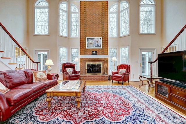 living room with a healthy amount of sunlight, a brick fireplace, and a high ceiling