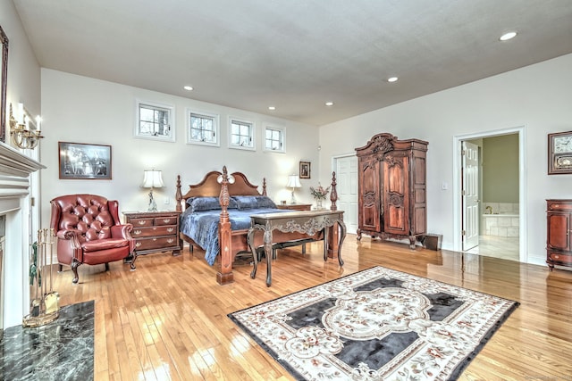 bedroom with a high end fireplace and hardwood / wood-style flooring