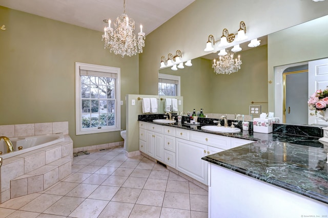 bathroom with toilet, vanity, tile patterned flooring, tiled tub, and a chandelier