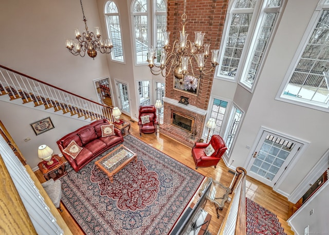 living room featuring hardwood / wood-style floors, a fireplace, a high ceiling, and a notable chandelier