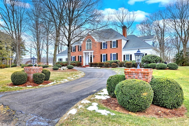 colonial-style house featuring a front lawn