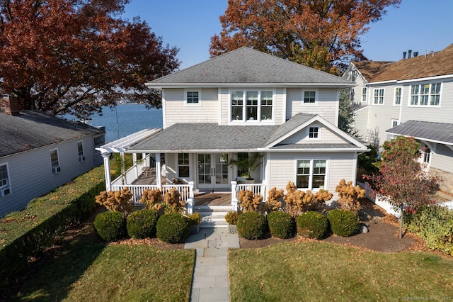 view of front facade featuring a front yard, a porch, french doors, and a shingled roof