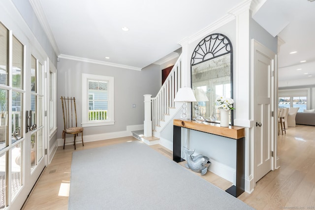 entryway featuring light wood finished floors, stairs, a wealth of natural light, and ornamental molding