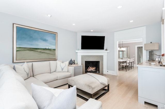 living area featuring light wood-style flooring, recessed lighting, a fireplace, and baseboards