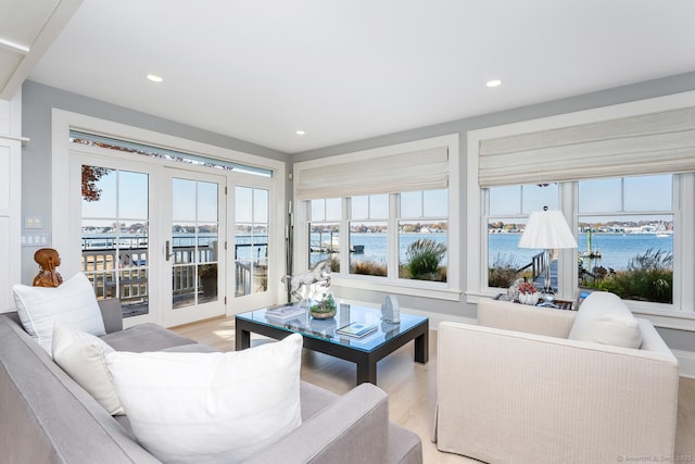 living area with recessed lighting, light wood-type flooring, and a water view