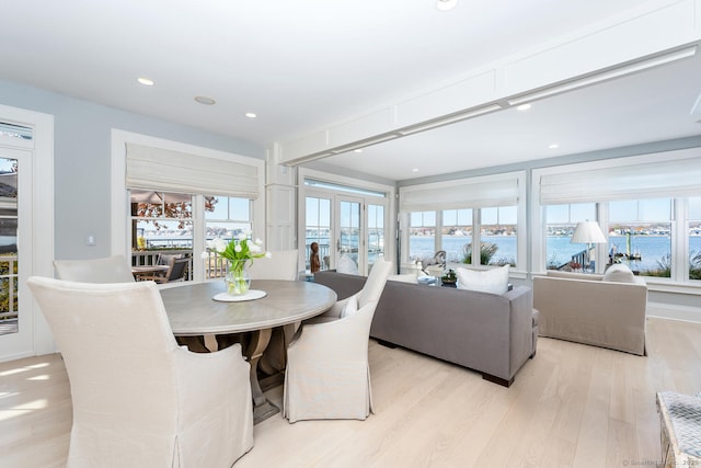 dining room featuring recessed lighting, a water view, and light wood-style flooring