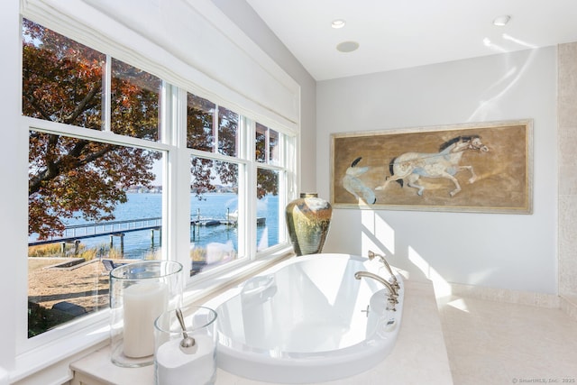 bathroom featuring recessed lighting, a water view, and a freestanding tub