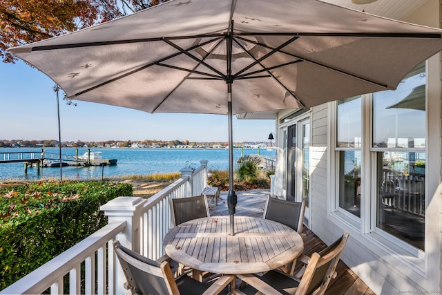 wooden deck with outdoor dining space, a dock, and a water view