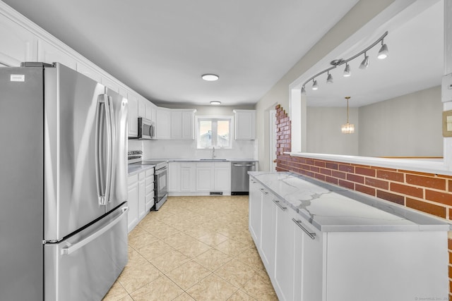 kitchen with white cabinets, backsplash, hanging light fixtures, stainless steel appliances, and light stone countertops