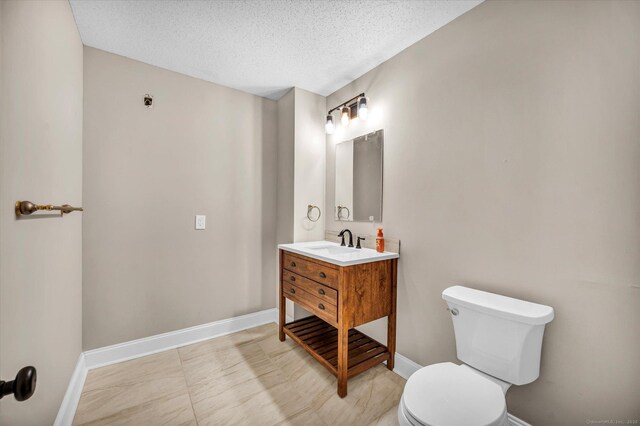 bathroom with a textured ceiling, vanity, and toilet