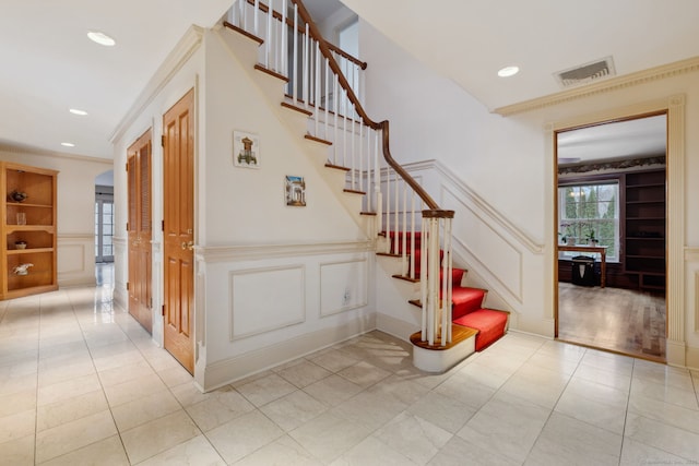 staircase featuring tile patterned floors, visible vents, built in features, and a decorative wall