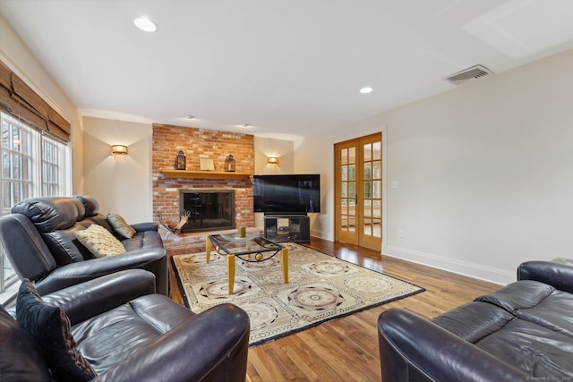 living area with wood finished floors, visible vents, baseboards, a fireplace, and french doors