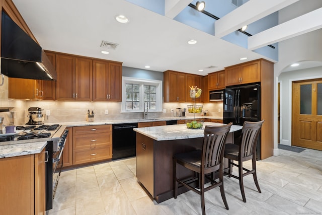 kitchen with light stone countertops, arched walkways, a sink, black appliances, and extractor fan