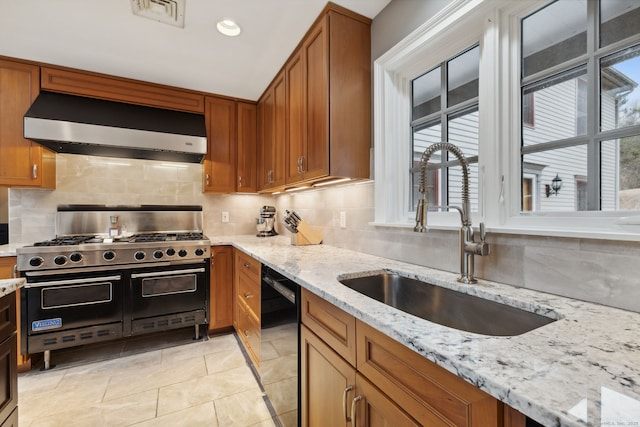 kitchen with visible vents, brown cabinets, black appliances, a sink, and exhaust hood