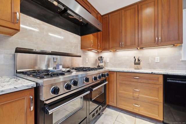 kitchen featuring light tile patterned floors, brown cabinetry, range with two ovens, black dishwasher, and wall chimney range hood