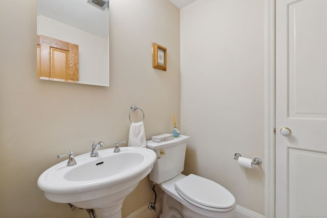 bathroom with visible vents, toilet, baseboards, and a sink