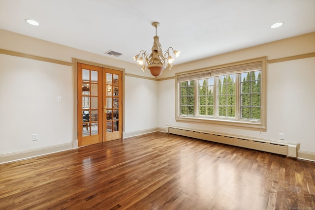 spare room featuring wood finished floors, visible vents, baseboards, an inviting chandelier, and a baseboard heating unit