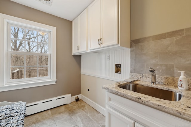 clothes washing area featuring a baseboard heating unit, baseboards, cabinet space, hookup for an electric dryer, and a sink