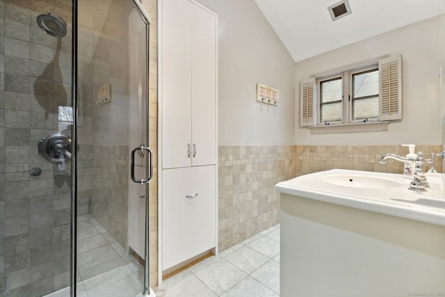 bathroom with tile patterned flooring, visible vents, a shower stall, vaulted ceiling, and tile walls