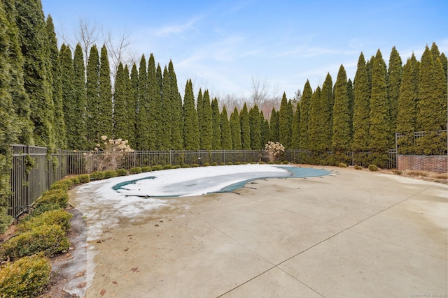 view of pool with a patio, fence, a fenced in pool, and a view of trees