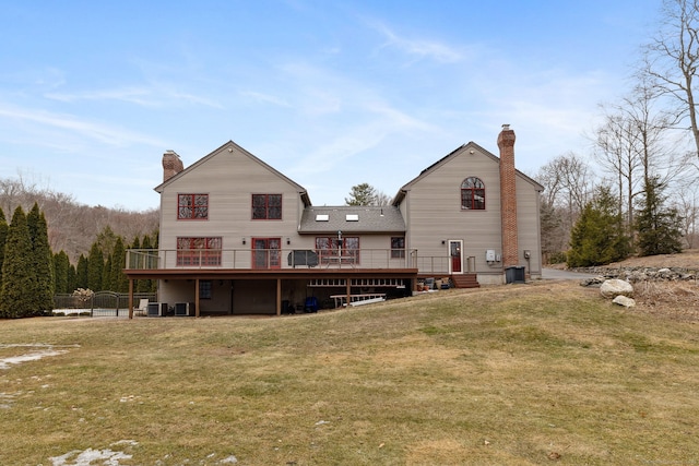 rear view of property featuring a wooden deck, a yard, and a chimney