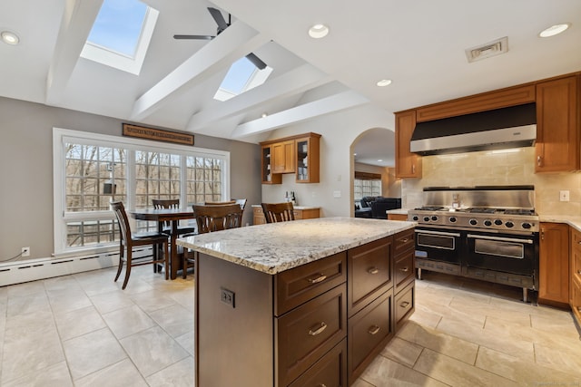 kitchen featuring backsplash, vaulted ceiling with beams, light stone countertops, double oven range, and range hood