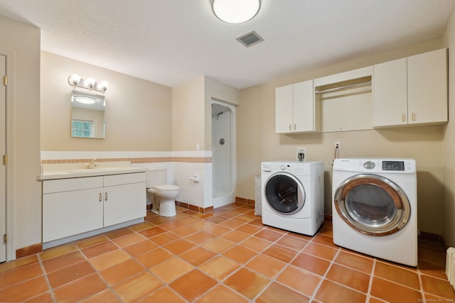 laundry area with light tile patterned floors, visible vents, a sink, a textured ceiling, and washing machine and dryer