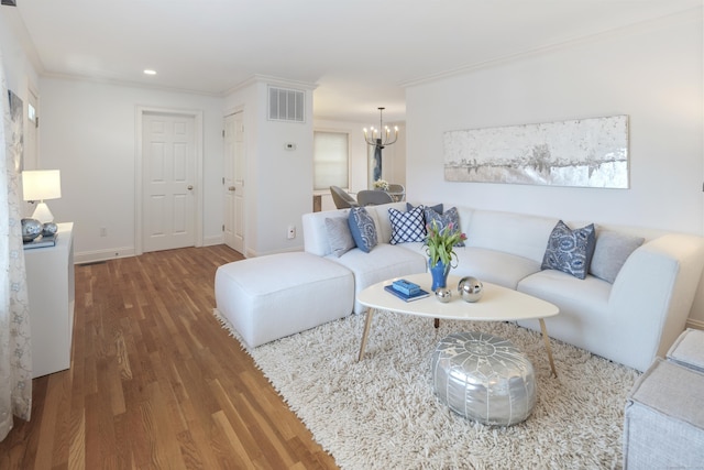 living room featuring crown molding, hardwood / wood-style flooring, a wealth of natural light, and an inviting chandelier