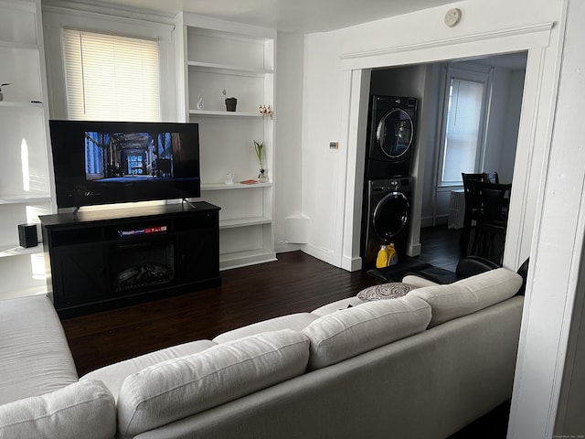 living room with stacked washing maching and dryer and dark wood-type flooring