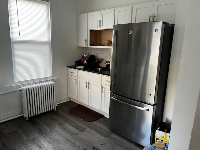 kitchen featuring tasteful backsplash, sink, stainless steel refrigerator, white cabinetry, and radiator heating unit