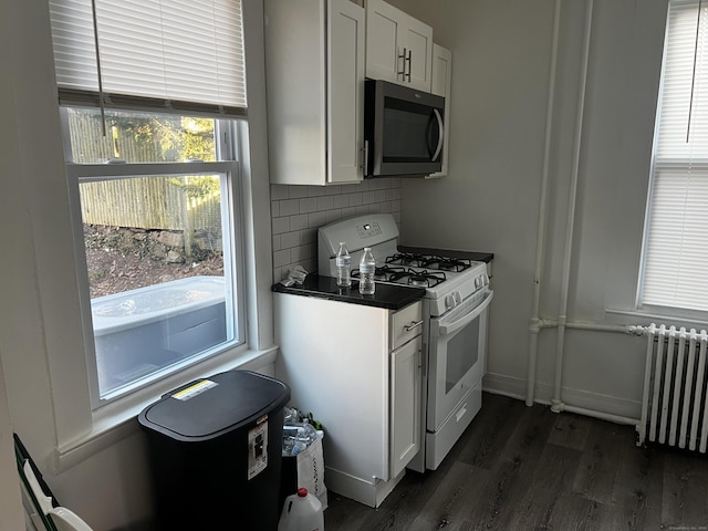 kitchen featuring radiator, dark wood-type flooring, white cabinetry, decorative backsplash, and white gas stove