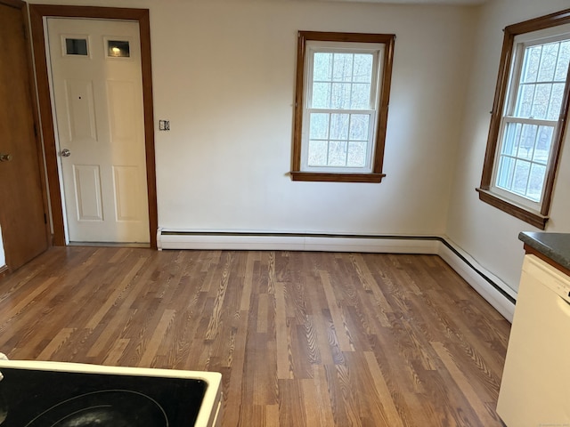 empty room with baseboard heating, a wealth of natural light, and dark hardwood / wood-style flooring