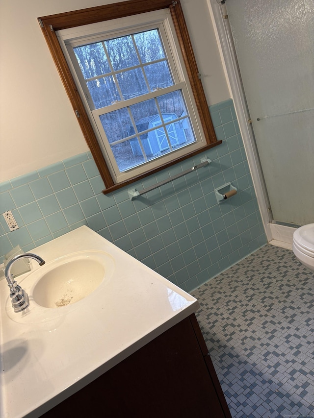 full bathroom featuring toilet, a stall shower, tile walls, and vanity