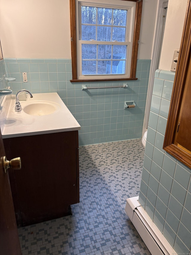 bathroom featuring a baseboard heating unit, vanity, tile walls, a shower stall, and tile patterned floors