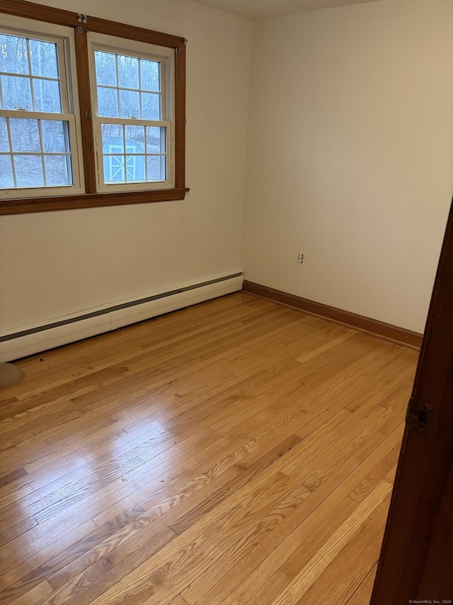 spare room featuring baseboard heating and light hardwood / wood-style flooring