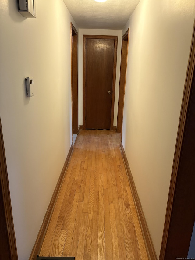 corridor with light wood-style flooring and baseboards