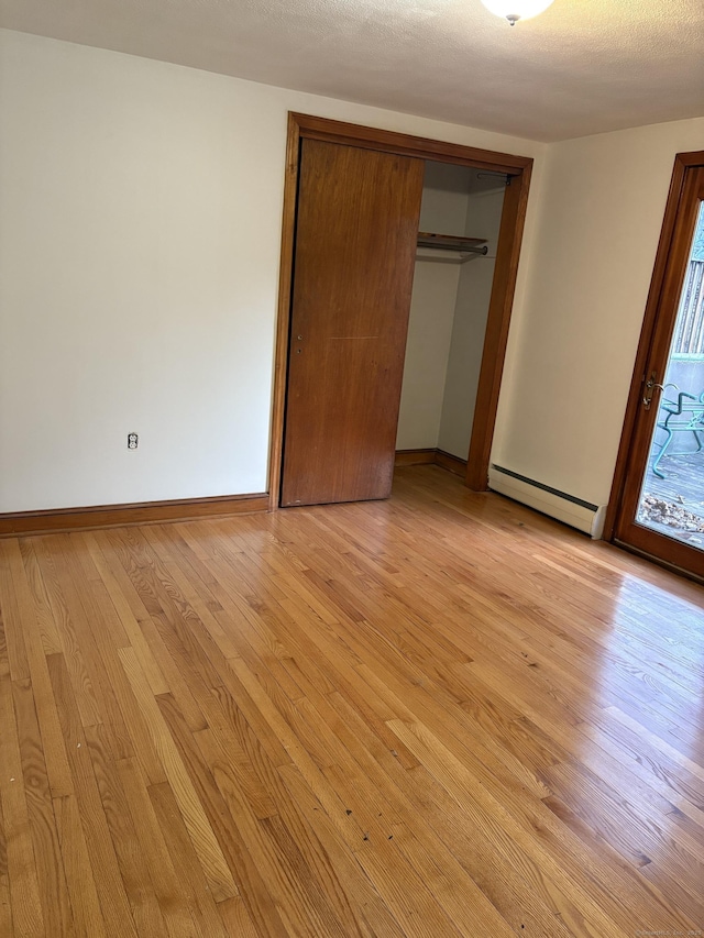 unfurnished bedroom with light wood-type flooring, a closet, and a baseboard radiator