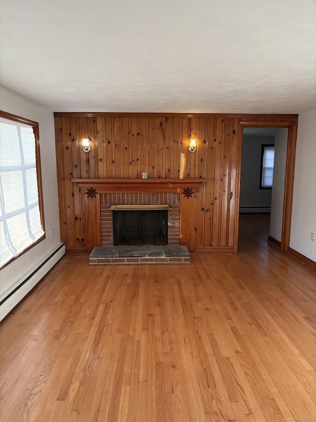 unfurnished living room featuring a brick fireplace, baseboard heating, baseboards, and light wood finished floors