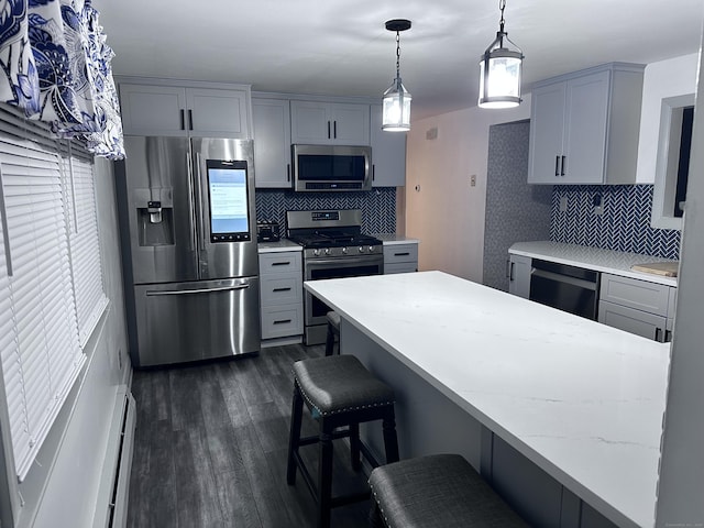 kitchen featuring decorative backsplash, gray cabinets, stainless steel appliances, and a breakfast bar area