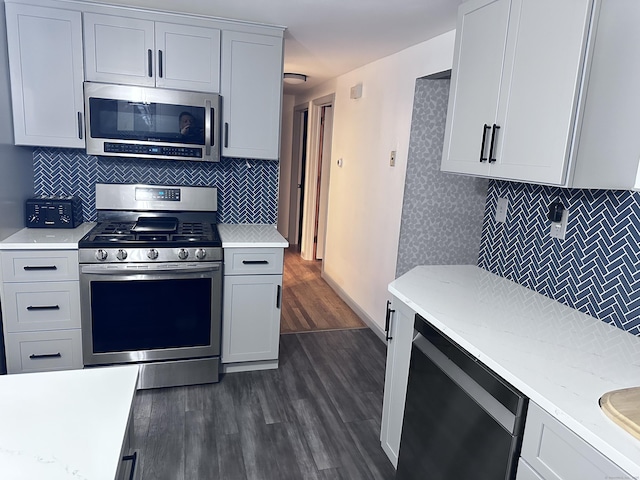 kitchen featuring white cabinetry, appliances with stainless steel finishes, dark hardwood / wood-style flooring, and backsplash