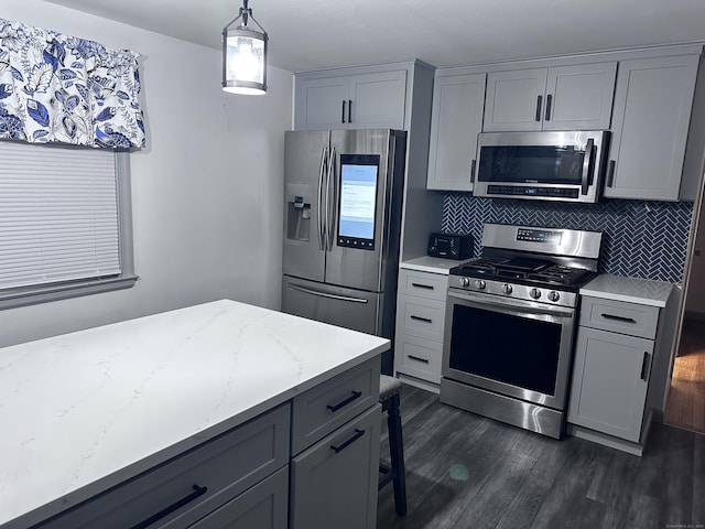 kitchen featuring decorative light fixtures, decorative backsplash, gray cabinetry, stainless steel appliances, and light stone counters