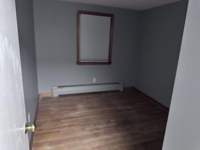 unfurnished room featuring hardwood / wood-style flooring and a baseboard radiator