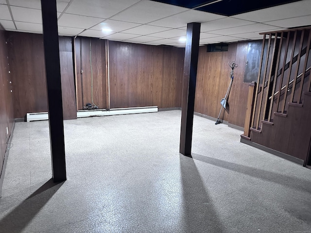 basement featuring a baseboard heating unit and wood walls